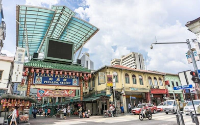 Jalan Petaling entrance in Kuala Lumpur, bustling street scene with shops and people.
