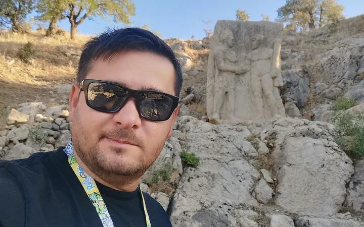 Cappadocia tour guide near ancient rock carvings in a rocky landscape.