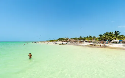 Holbox Island beach with clear turquoise water and palm trees, Mexico.