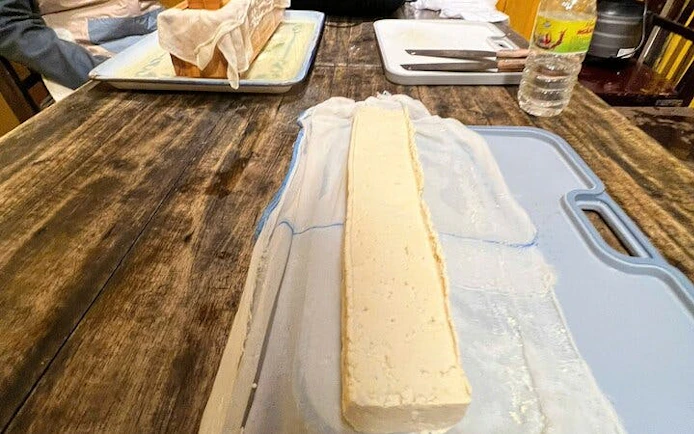Tofu block on a cutting board during Sa Pa cooking class using local Vietnamese ingredients.