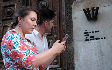 Visitors using a smartphone for a self-guided exploration game in Pisa, Italy.
