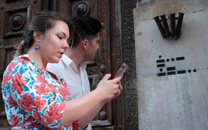 Visitors using a smartphone for a self-guided exploration game in Pisa, Italy.