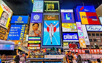 Dotonbori neon signs in Osaka, featuring the iconic Glico running man, part of a guided food tour.