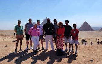 Group of tourists with Egyptologist at Saqqara pyramids during guided tour.