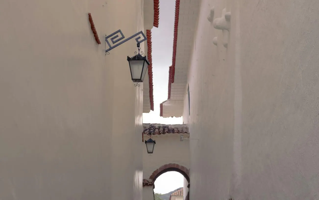 Narrow alley with white walls and traditional lanterns in Cusco's San Blas district.
