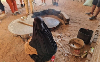 Woman preparing traditional bread on open fire during ATV safari in Sharm El Sheikh.