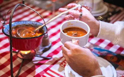 Hungarian goulash served in a pot and cup during Budapest food tour with local wines.
