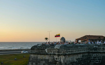 Cartagena Walled City at sunset with Colombian flag and ocean view.