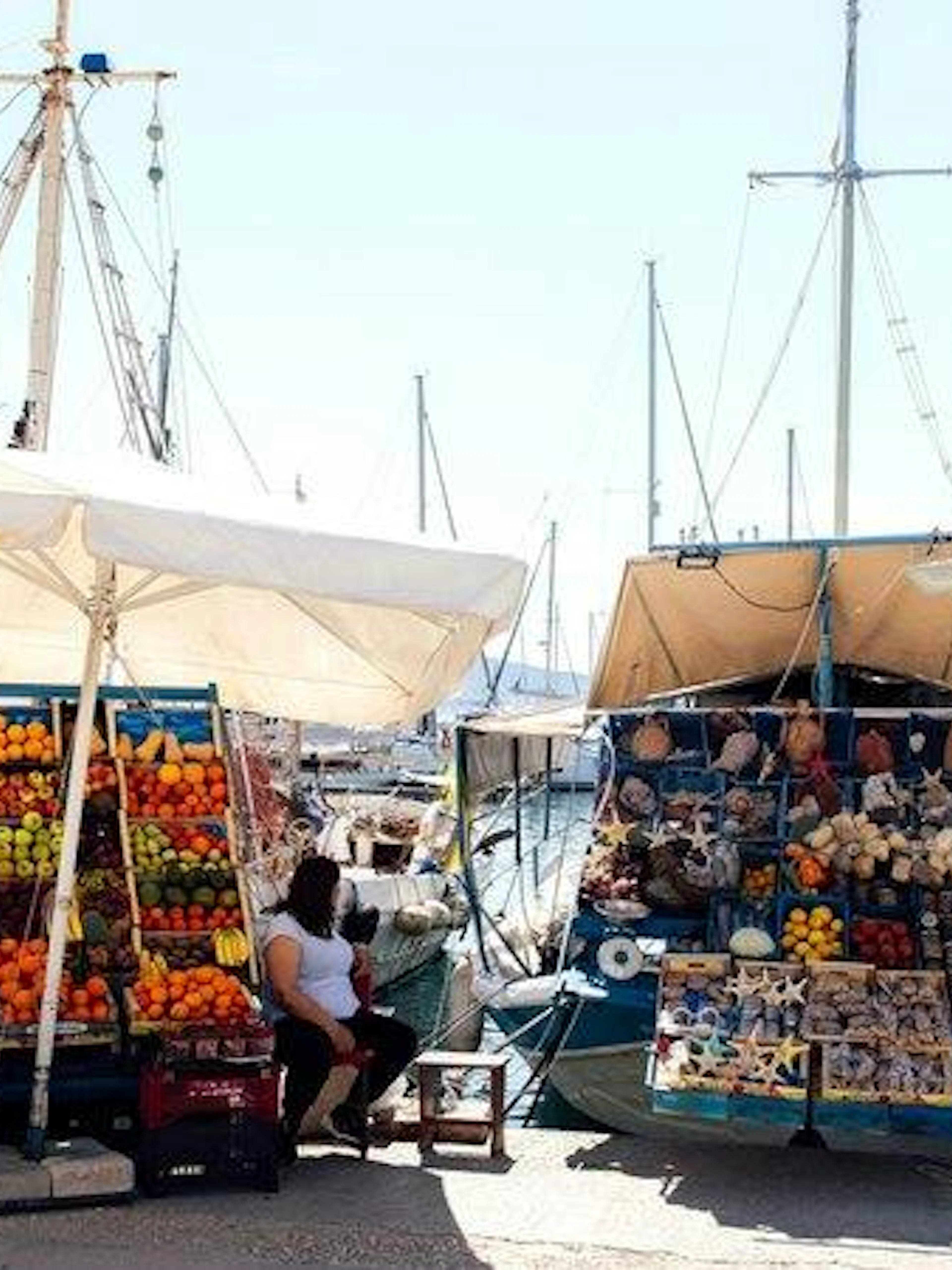 Dockside market with fresh produce and souvenirs on boats, Agistri, Greece.
