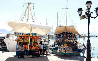 Dockside market with fresh produce and souvenirs on boats, Agistri, Greece.