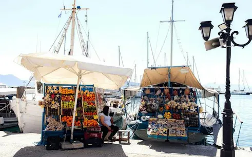 Dockside market with fresh produce and souvenirs on boats, Agistri, Greece.