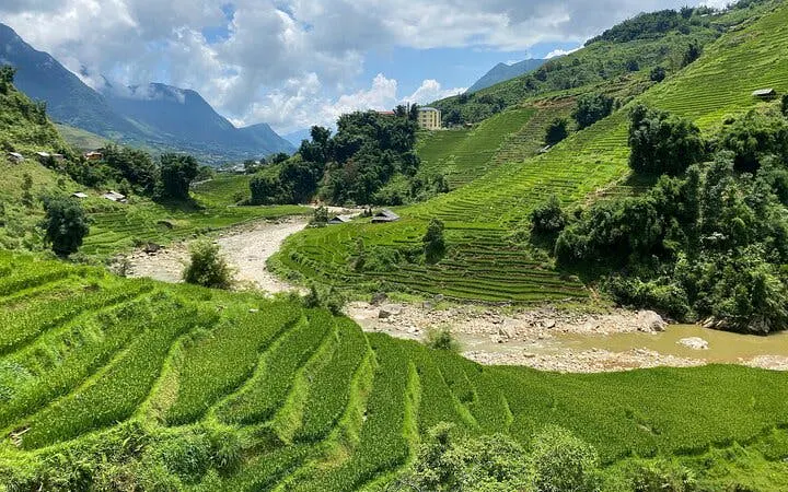 Terraced rice fields on Y Linh Ho trail, Sapa, with mountains and river in the background.
