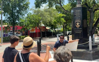 Tour guide explaining Bay of Pigs monument to visitors in Little Havana, Miami.