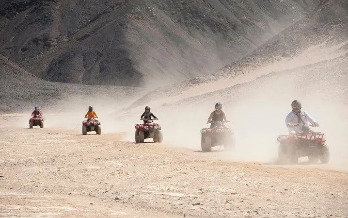 Quad biking adventure in Sharm El Sheikh desert with group riding through sandy terrain.