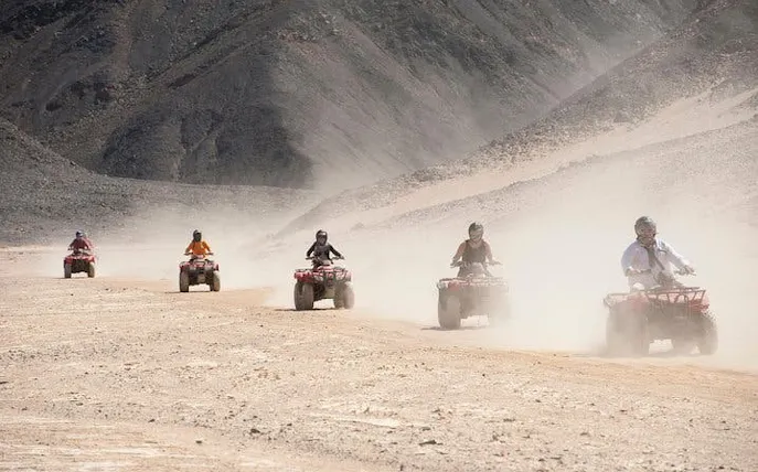 Quad biking adventure in Sharm El Sheikh desert with group riding through sandy terrain.