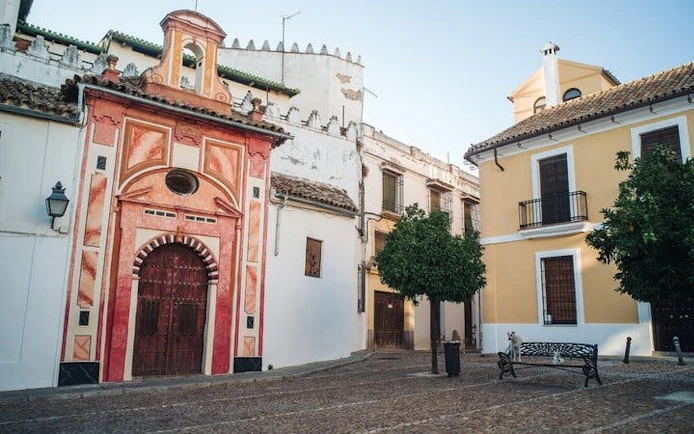Historic buildings in a Cordoba plaza, featuring colorful facades and a cobblestone street.
