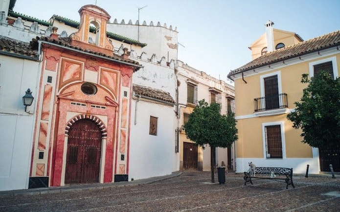 Historic buildings in a Cordoba plaza, featuring colorful facades and a cobblestone street.