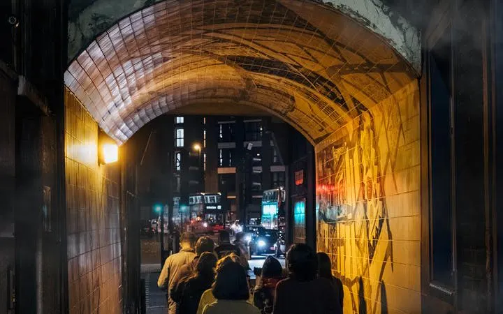 Group walking through a dimly lit London alley on Jack the Ripper tour.