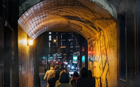 Group walking through a dimly lit London alley on Jack the Ripper tour.