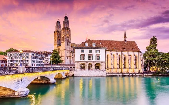 Grossmünster church and Limmat River at sunset, Zurich Self-Guided Walking Tour.