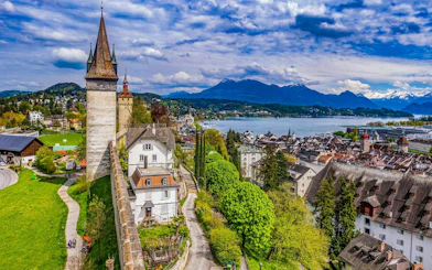 Lucerne Old Town with city walls and towers, overlooking Lake Lucerne and mountains.