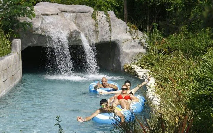 Visitors floating on inner tubes through a cave with waterfalls in Punta Cana's hidden cenotes.