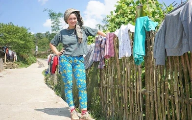 Traveler on a rural path in Sapa, Vietnam, with clothes drying on a bamboo fence.