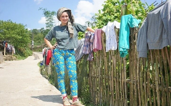 Traveler on a rural path in Sapa, Vietnam, with clothes drying on a bamboo fence.
