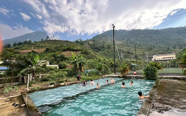 People swimming in a pool with mountain views on a Sapa motorbike tour, Cat Cat Village, Vietnam.
