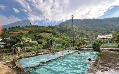 People swimming in a pool with mountain views on a Sapa motorbike tour, Cat Cat Village, Vietnam.