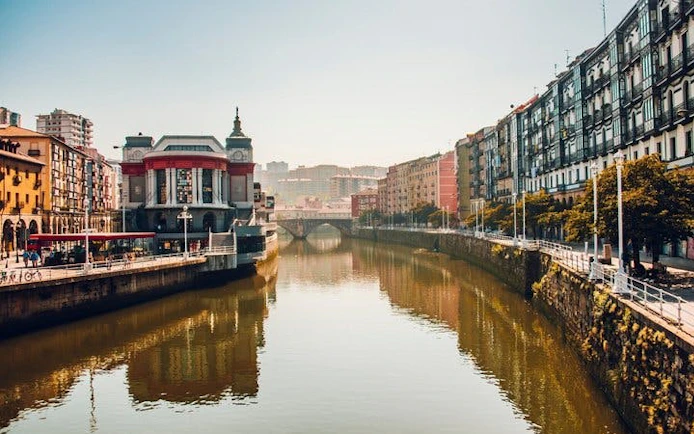 Bilbao river view with historic buildings and bridge on self-guided walking tour.
