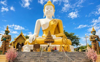 Buddha statue at Wat Doi Suthep, Chiang Mai, with ornate temple details and blue sky.