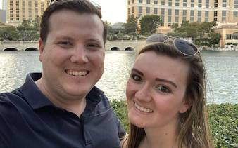 Couple smiling in front of Bellagio fountains on Las Vegas Strip.