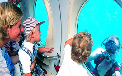 Family observing diver through submarine window on Tenerife tour.