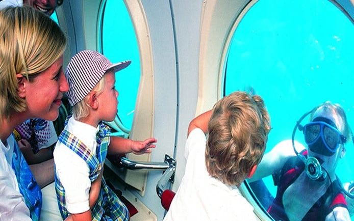 Family observing diver through submarine window on Tenerife tour.