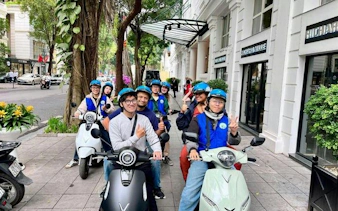 Group on e-scooters exploring Hanoi streets during city tour with street food and drinks.