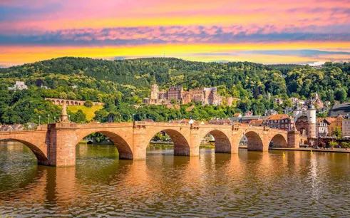 Heidelberg Castle and Old Bridge over Neckar River during sunset on self-guided walking tour.