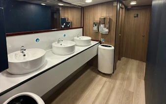 Restroom facilities on Malta boat cruise with modern sinks and wooden decor.