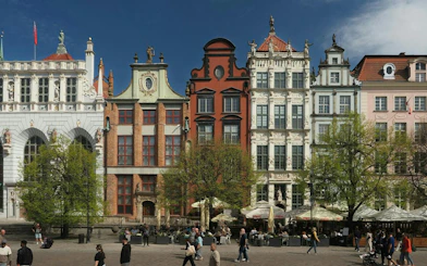 Colorful historic buildings in Gdansk Old Town with people walking and dining outdoors.