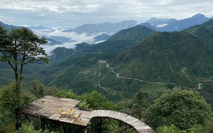 Mountain view from Sapa with wooden deck overlooking valley and winding road.