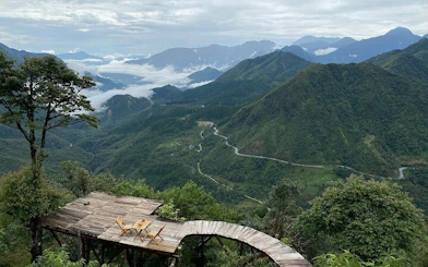 Mountain view from Sapa with wooden deck overlooking valley and winding road.