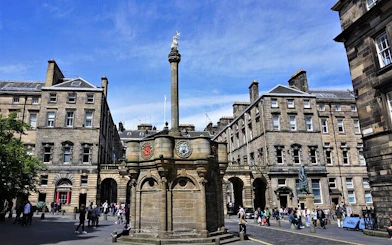 Edinburgh city square with historic buildings and a central monument.