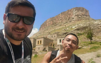 Cappadocia tour participants in front of ancient rock formations and historic buildings.
