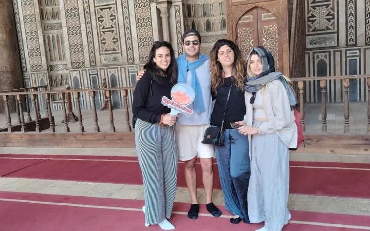 Group of tourists inside the Citadel of Saladin, Cairo, with intricate wall designs in the background.