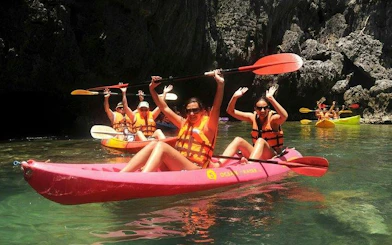Kayakers in Ang Thong National Marine Park, Koh Samui, paddling near rocky cliffs.