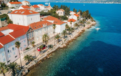Korcula coastline with red-roofed buildings and clear blue sea, Croatia.