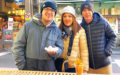 Visitors enjoying food samples at Kyoto's Nishiki Market during a private tour.