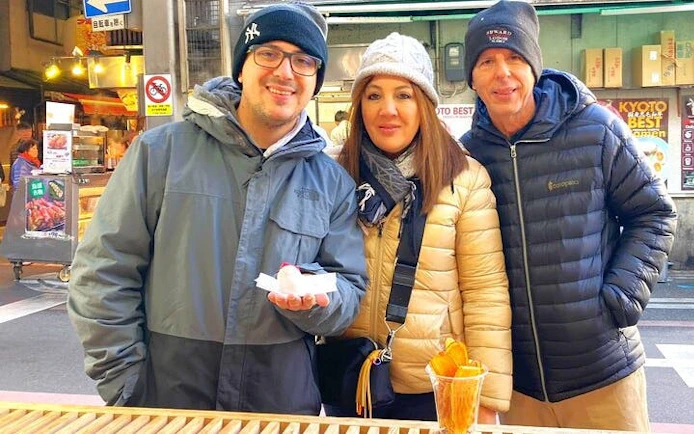 Visitors enjoying food samples at Kyoto's Nishiki Market during a private tour.