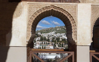 Granada cityscape viewed through Alhambra's ornate archway on self-guided walking tour.