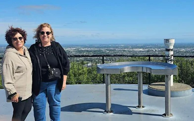 Two people standing at a scenic viewpoint overlooking Christchurch city on a half-day tour.